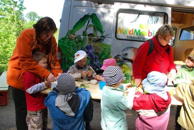 Kita-Kinder basteln vor dem WaldMobil