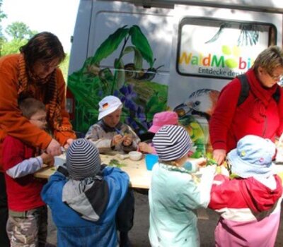 Kita-Kinder basteln vor dem WaldMobil